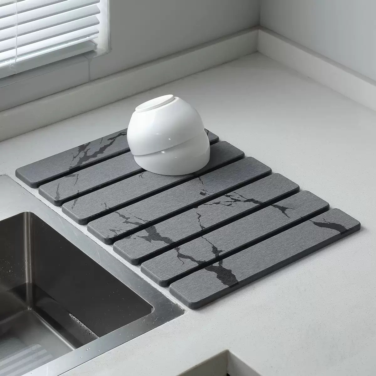 Dark grooved diatomite hard mat shown beside a kitchen sink